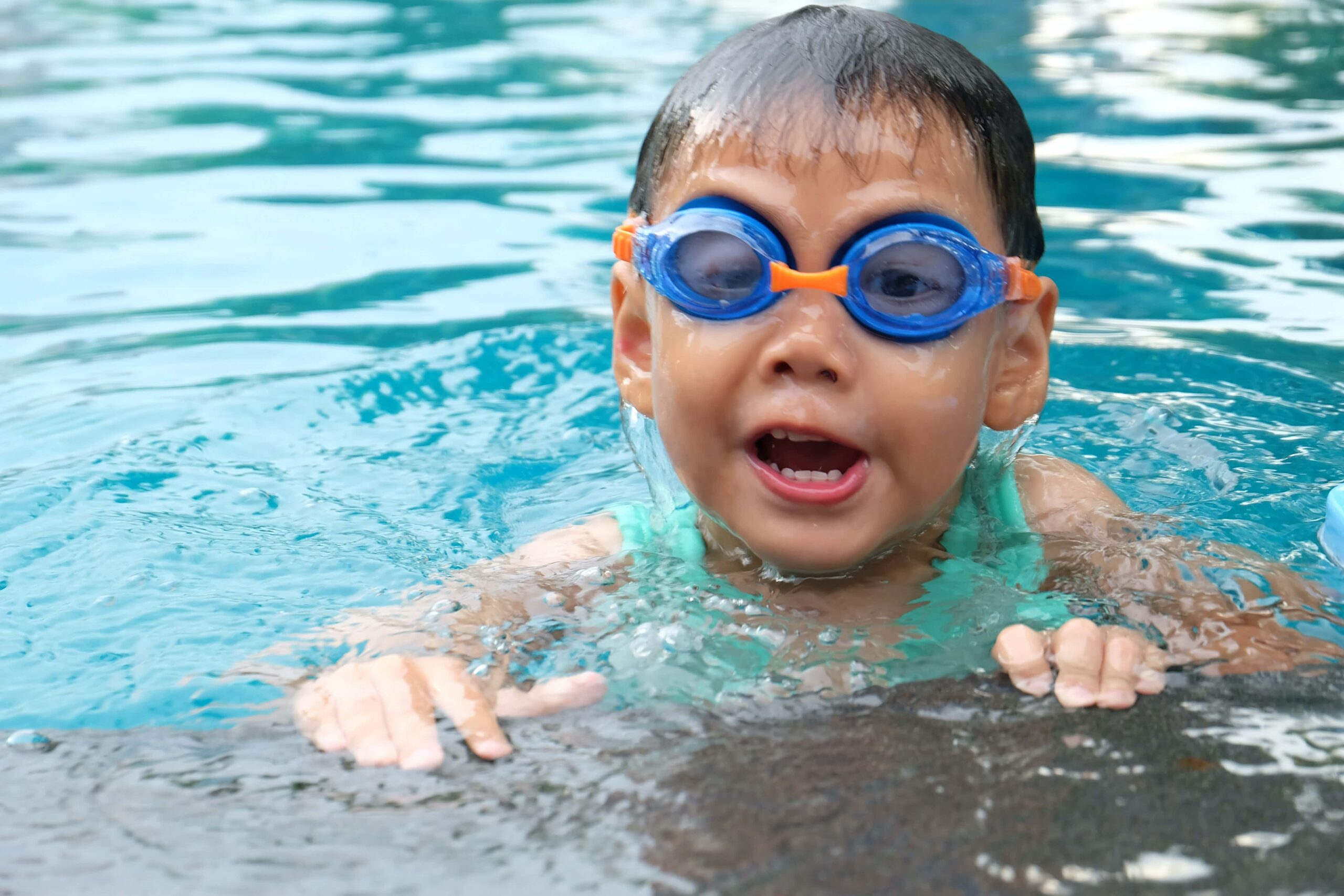 Little kid swimming with goggles