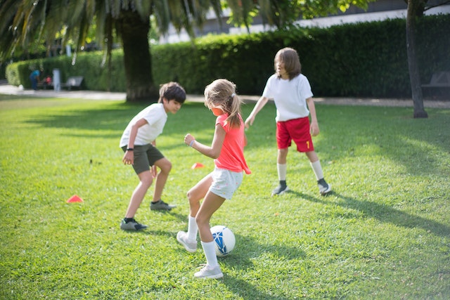 Three kids playing soccer outside