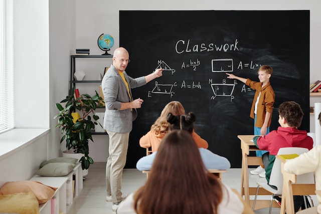 Kids in classroom with teacher chalkboard