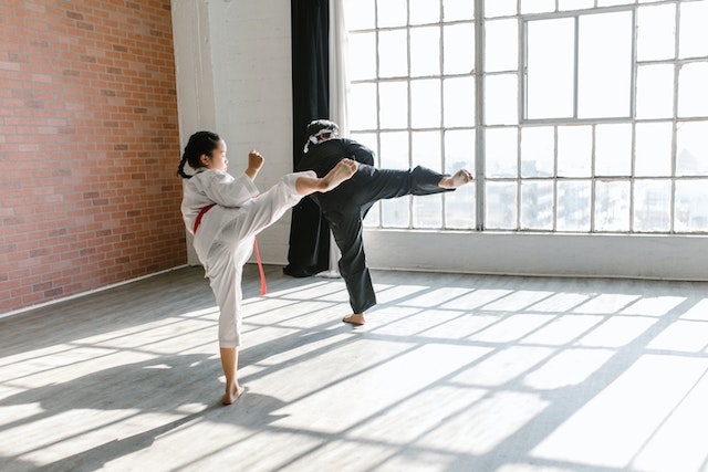 Kid learning karate with instructor kicking