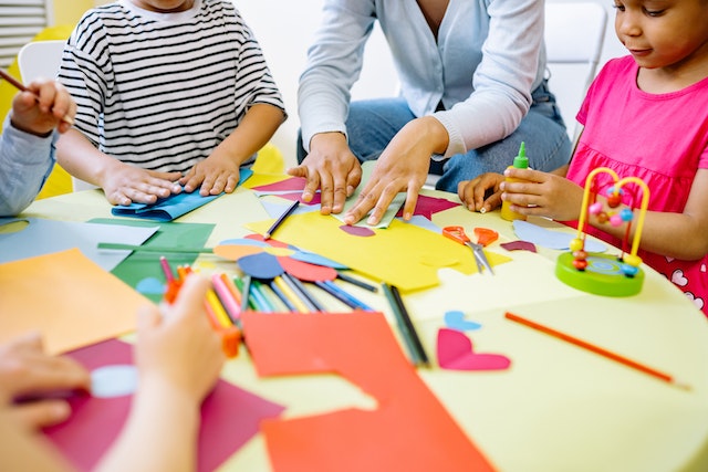 Kids on table with construction paper for art