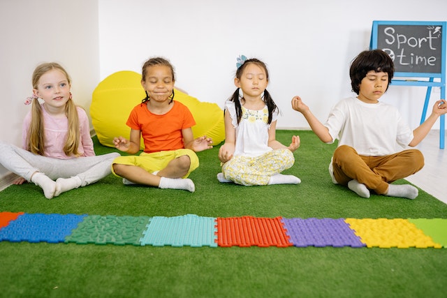 4 kids practicing yoga on floor sitting