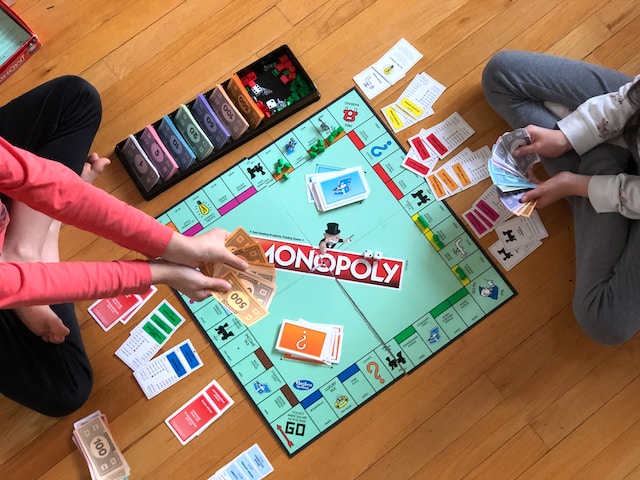 People playing monopoly on the floor; board game; game night